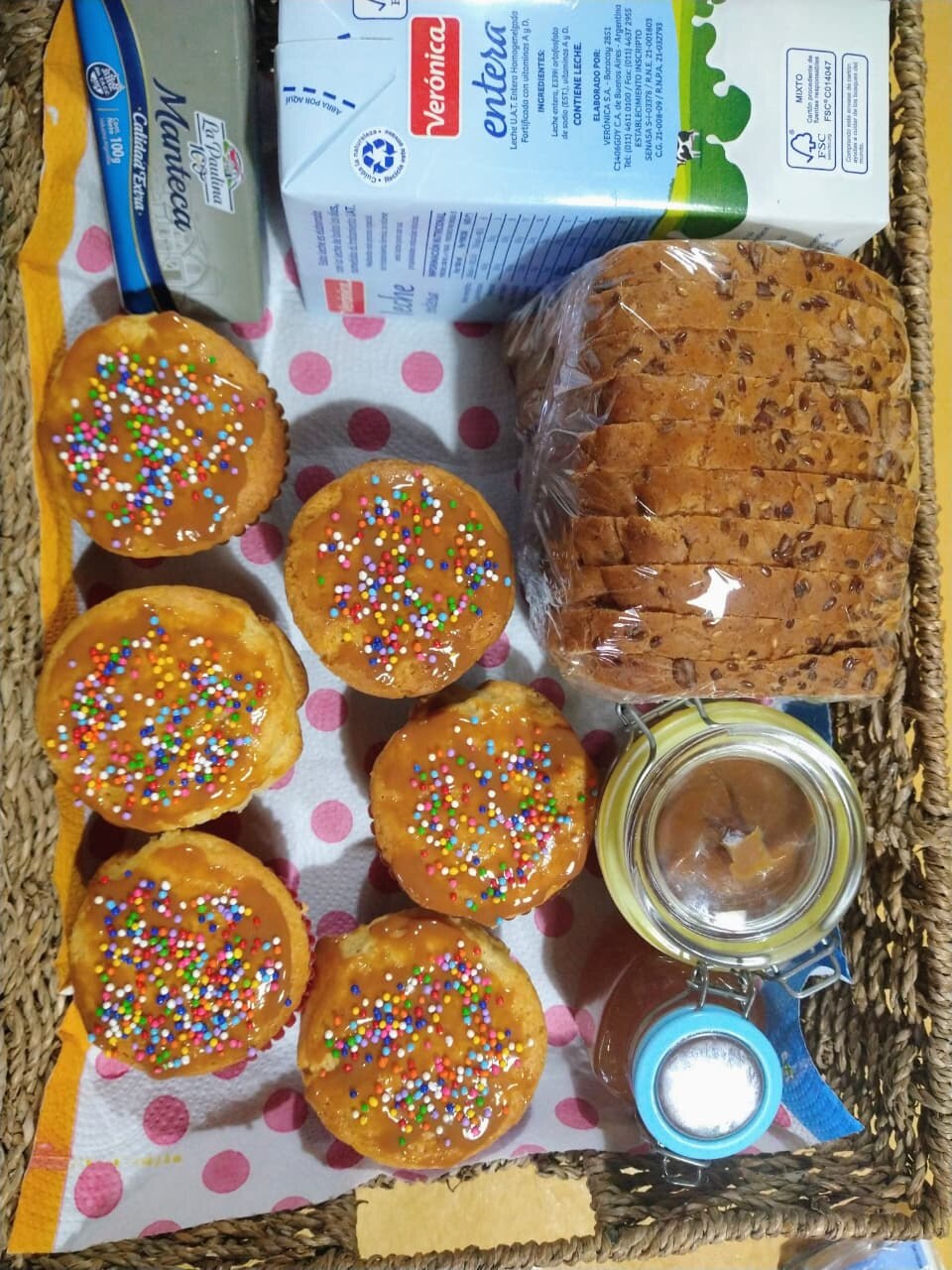 Canasta de desayuno con muffins bañados en dulce de leche, pan de semillas, leche y manteca