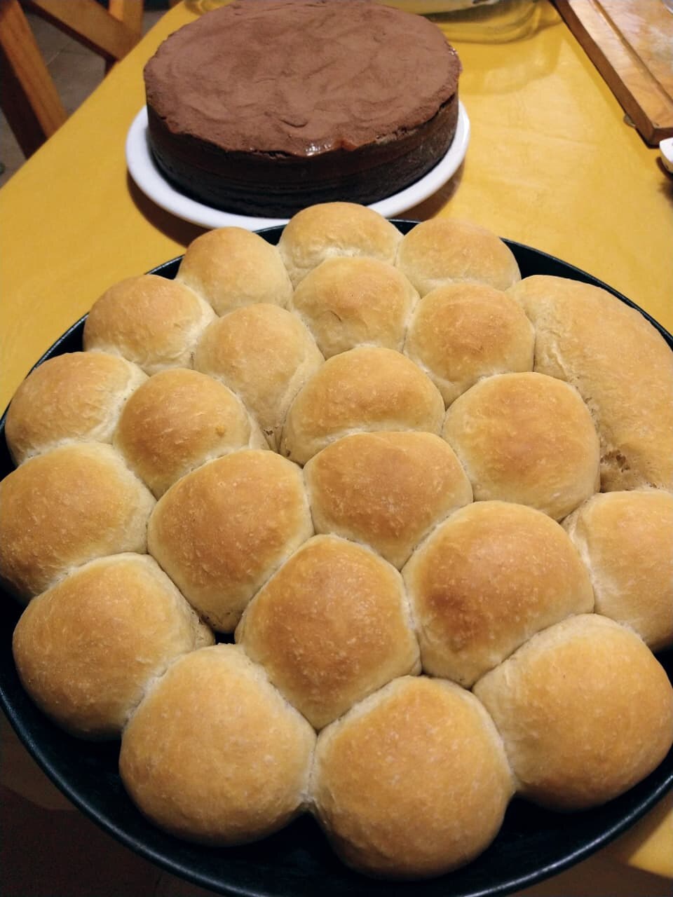 Fuente de pancitos caseros recién horneados y una torta de chocolate